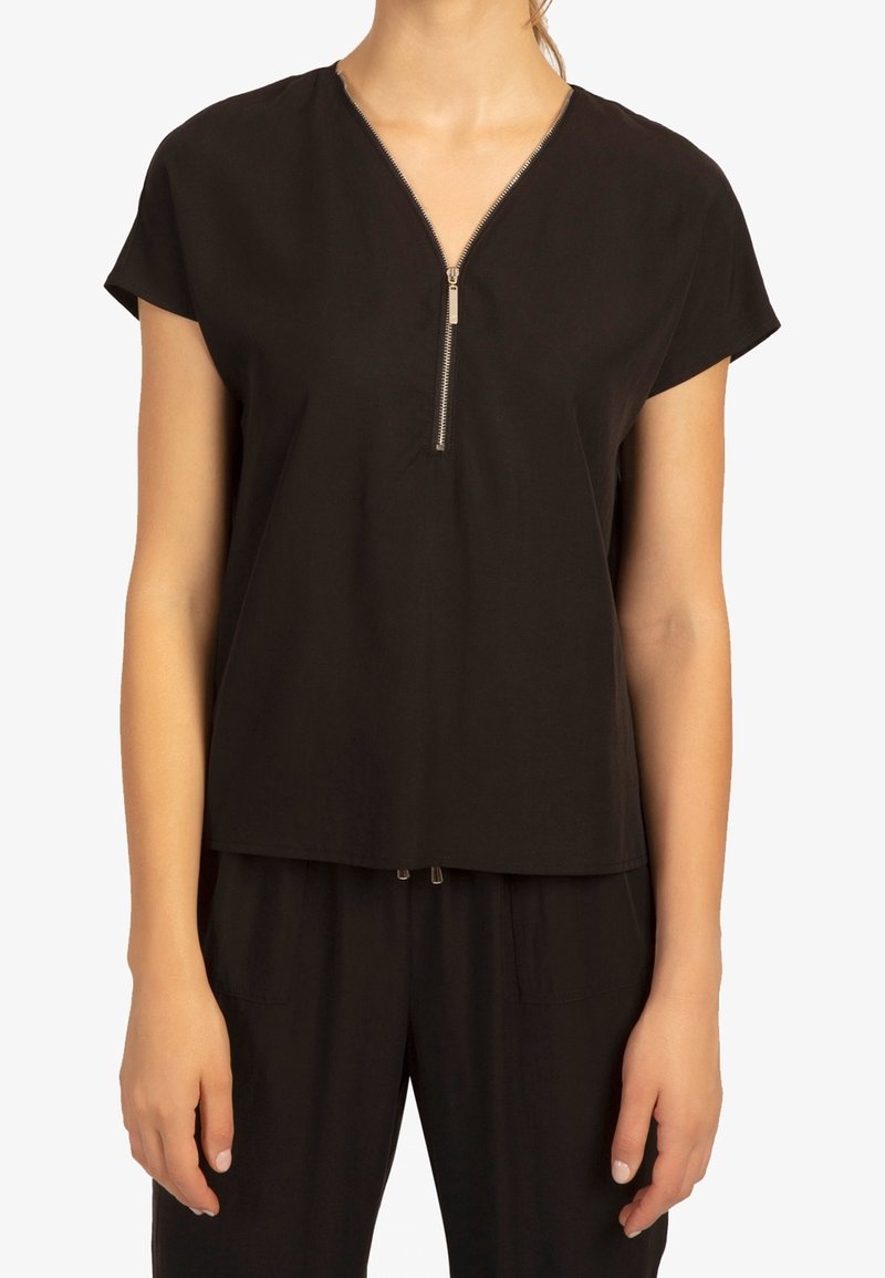 Top corto nero con maniche corte, presenta un scollo a V con una zip metallica, vestibilità rilassata e tessuto morbido. Il design presenta una caduta sottile e nessun motivo.