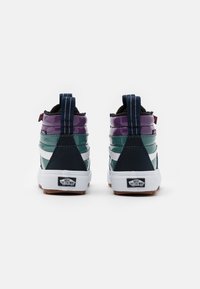 Höga sneakers i marinblå, grön och lila lackskinn med vita ränder. Har vadderad krage, textilmaterial och gummisula.