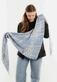 Sciarpa a motivi blu e bianchi con una consistenza morbida, tenuta in forma triangolare, con un'etichetta su un lato.