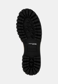 Suola di scarpa in gomma nera con scanalature profonde e un logo centrale. Presenta scanalature e motivi per migliorare la trazione. Il testo vicino al tallone indica la taglia e il marchio.