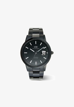 Čierne nerezové automatické hodinky s tmavou čelom, s luminiscenčnými hodinovými markerami a zobrazením dátumu na 3. hodine. Vodotesné do hĺbky 100 m.