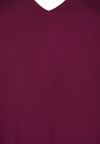 Mörkröd v-neck topp gjord av ett lätt och glatt tyg. Har en enkel och stilren design med en subtil glans och utan mönster eller utsmyckningar.