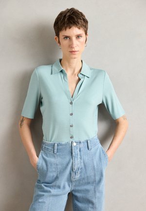 Lichtblauw kort mouw polo-shirt met een kraag, voorzien van een knopenlijst aan de voorkant en een zachte textuur, gecombineerd met hoog-getailleerde denim broeken.