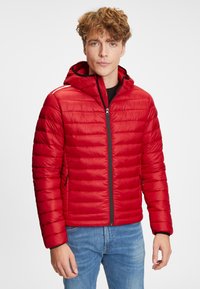 Rød puffjakke med hætte, med quiltet design, frontlynlås og sidelommer. Sorte detaljer langs lynlåsen og hætten.
