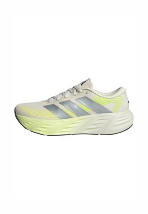Chaussure de course Adidas beige clair avec bandes argentées, accents jaune fluo, semelle rembourrée et fermeture à lacets, vue de côté.
