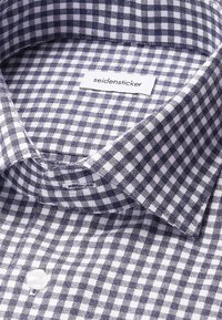 Camicia a quadri blu navy e bianca con colletto classico e chiusura con bottoni. Realizzata in tessuto leggero con una texture liscia.