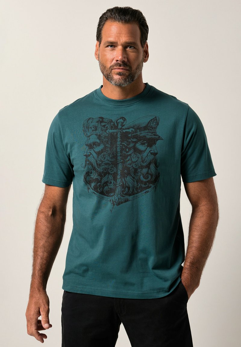 Camiseta de algodón color verde azulado con una impresión gráfica negra de dos caras con elementos ornamentados. Mangas cortas, cuello redondo y un corte holgado.