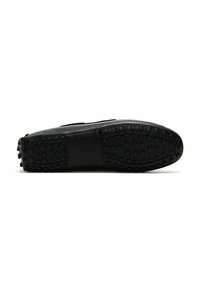 Zapato de cuero negro con empeine liso, punta redondeada y suela de goma texturizada con tachuelas redondeadas para mayor agarre.