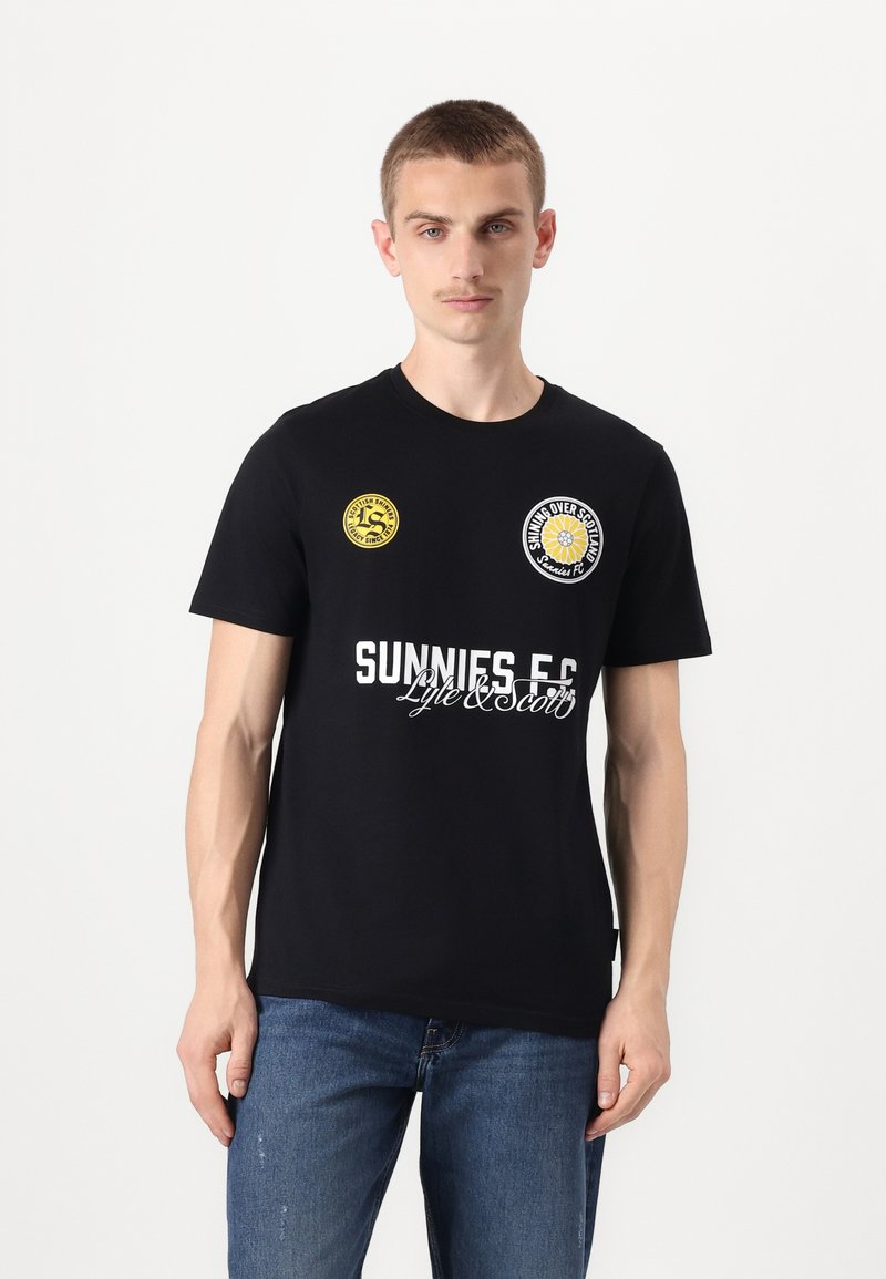 T-shirt noir à manches courtes avec des logos circulaires jaunes et blancs. Le texte indique "SUNNIES E.C." en lettres blanches en gras en bas.