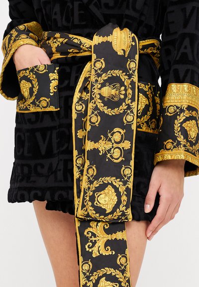 Schwarzer Umhang mit goldfarbigem Barockmuster. Verfügt über einen gebundenen Gürtel und eine Tasche, strukturierter Stoff und dekorative Ärmel mit filigranen Mustern.