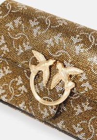 Gold and black clutch bag featuring a textured surface embellished with rhinestones and a gold bird-shaped clasp. Floral pattern detail.