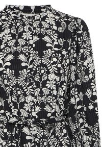 Vestido de tela negra con un estampado floral blanco, mangas largas, un escote alto y un detalle de cintura anudada con cierres de botón.