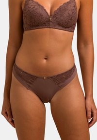 Brassière en dentelle marron avec motif floral, dotée d'un décolleté en V profond et d'un subtil accent doré au centre. Bas de bikini en dentelle marron assorti.