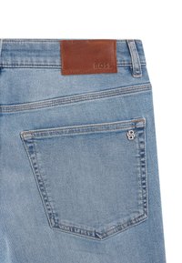 Svetlomodré rifle z denimu s hnedou koženou nášivkou s nápisom "BOSS" na páse. Jedna zadná kapsa s malým kovovým doplnkom.