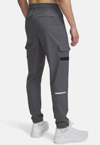Graue Cargo-Hosen mit elastischem Bund, mehreren Seitentaschen und reflektierenden Akzenten. Hergestellt aus einem glatten, leichten Material.