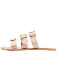 Sandali piatti in pelle nudi con tre cinturini regolabili, dotati di fibbie rettangolari in tono oro e una suola liscia e flessibile.
