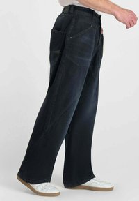 Zwarte denim broek met wijde pijpen, grote opgestikte zakken, versterkte stiksels en een rechte snit. Heeft een gladde textuur en stevige stof.