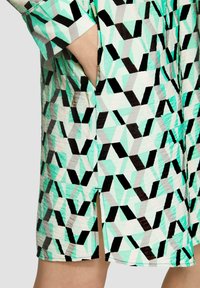 Kurzes, gemustertes Kleid mit geometrischen Formen in Mint, Schwarz und Grau. Mit Seitentaschen und einem Schlitz am Saum. Leichter Stoff.