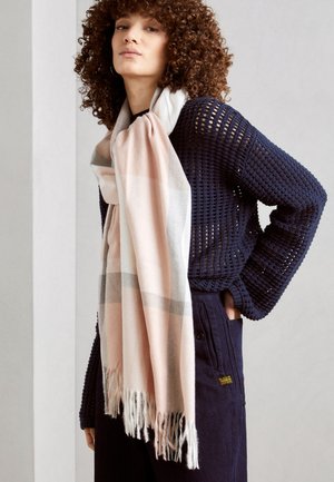 Lightweight, check-pattern scarf in soft pastel pink, grey, and white. Finished with fringed edges. Worn over a dark, knit sweater.