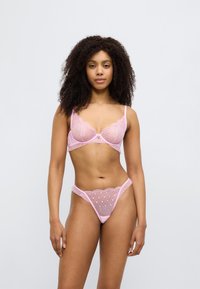 Σετ ροζ εσώρουχα με δαντέλα, που περιλαμβάνει διάφανα κορμάκια και ταυτόχρονο σλιπ, διακοσμημένα με διαμαντοειδές δίχτυ και κυματιστές άκρες.