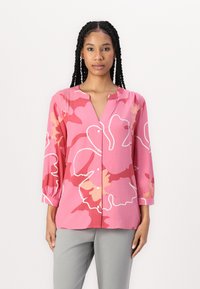 Rosa Blumenshirt mit weißem Rand, V-Ausschnitt, langen Puffärmeln und Knöpfen auf der Vorderseite. Weicher, leichter Stoff.