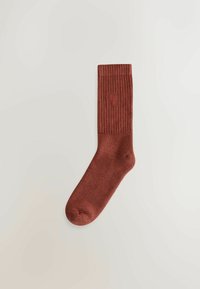 Red ribbed sock with a solid texture, featuring a reinforced toe and a small logo near the top. Cotton blend material.