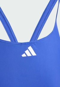 Plavi sportski kupaći kostim s tankim ukriženim naramenicama i bijelim Adidas logotipom, izrađen od glatkog, rastezljivog materijala.