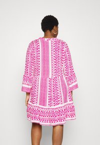 Vestido rosa con estampado, de mangas tres cuartos, que presenta diseños geométricos y una falda acampanada, con acentos blancos y un acabado texturizado.