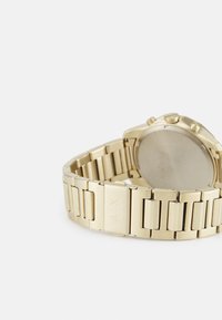 Reloj de acero inoxidable con tono dorado, pulsera de eslabones, superficie texturizada y caja redonda. Presenta tres pulsadores y un fondo liso.