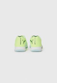 Chaussures de sport avec une tige synthétique jaune-vert vif, semelle blanche et une marque contrastante vert foncé à l'arrière. Semelle extérieure en caoutchouc texturé.