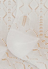 White lace fabric featuring a geometric pattern with diamond shapes and leaf motifs, showing openwork design and intricate stitching.