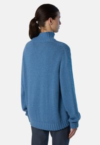 Maglione lavorato a maglia azzurro chiaro con colletto alto, vestibilità ampia e polsini e orlo ribattuti. Texture liscia e colore uniforme senza motivi.