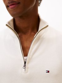 Pullover leggero a mezzo zip in crema chiaro con lavorazione a maglia testurizzata, dotato di dettagli in metallo argentato e di un piccolo logo ricamato in rosso, bianco e blu.
