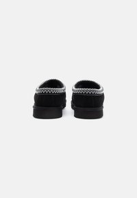 Bottines en suède noir à enfiler, avec une couture texturée en argent le long du col et une semelle plate en caoutchouc noir.