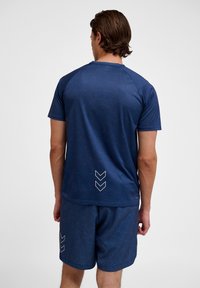 Marineblauw sportshirt met geometrische patronen, korte mouwen en een chevrondetail aan de onderrug. Zacht, lichtgewicht materiaal.