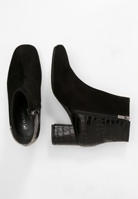 Botines de ante negro con un acento de cuero con patrón de cocodrilo y cierre de cremallera. Diseño de tacón ancho, textura suave y forma elegante.