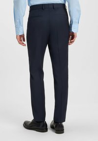 Pantaloni da dress navy realizzati in tessuto liscio. Slim fit con due tasche posteriori. Abbinati a scarpe nere e una camicia dress azzurro chiaro.