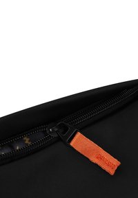 Černý látkový pytlík s černým zipem a oranžovým látkovým úchytem, s texturovaným povrchem a jemným vnitřním vzorem.