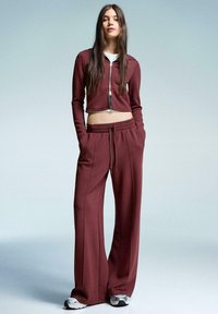 Bordeaux cropped zip-up jack en bijpassende wijde broek, beide van zachte stof, met een elastische tailleband en zijzakken.