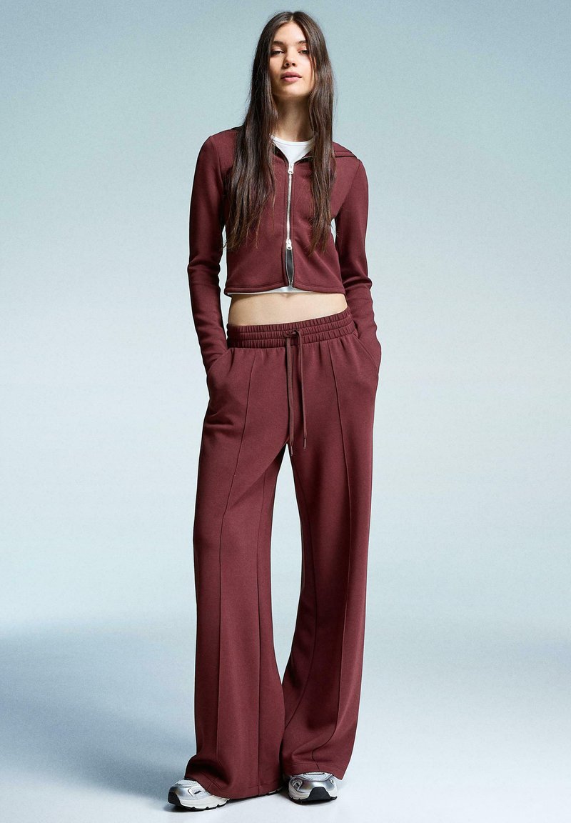 Bordeaux cropped zip-up jack en bijpassende wijde broek, beide van zachte stof, met een elastische tailleband en zijzakken.