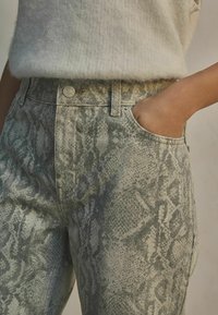 Slangenhuidpatroon jeans in tinten van groen en grijs, met een hoge taille, zakken en metalen knoopsluiting. Zachte, gestructureerde stof.