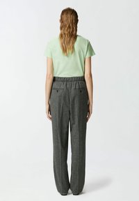 Svijetlozelena košulja kratkih rukava u kombinaciji s visokostrukim sivim širokim hlačama s teksturom. Ima elastičnu traku u struku i stražnje džepove.