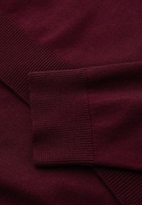 Pull en tricot bordeaux avec des poignets et un col côtelé. Texture lisse, design ajusté et coutures propres, adapté à un usage décontracté.