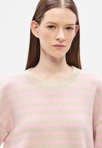 Πλεκτό πουλόβερ σε μπεζ με οριζόντιες ροζ ρίγες. Διαθέτει ριμπ λαιμόκοψη και μαλακή υφή, κατάλληλο για καθημερινή χρήση.