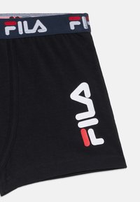 Bóxer de algodón negro con una cinturilla flexible que presenta un logo en blanco y rojo. Textura suave y diseño ajustado.