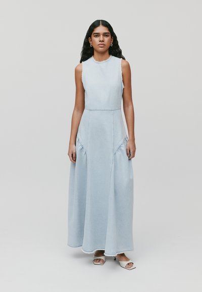 Robe maxi en denim bleu clair, sans manches, avec des détails froncés sur les côtés et des coutures. Texture lisse avec une coupe ample.