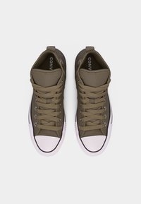 Par smeđih visokih Converse tenisica s bijelim gumenim vrhovima prstiju i vezicama, prikazane odozgo na bijeloj pozadini.