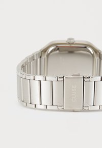 Silver stainless steel watch with a rectangular case, link bracelet, and clasp featuring subtle engraving. Smooth texture and polished finish.