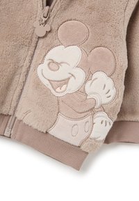 Chaqueta con capucha en color beige, hecha de suave forro polar, que presenta un bordado texturizado de Mickey Mouse en el frente. Incluye una cremallera y puños acanalados.