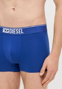 Μπλε ανδρικά εσώρουχα τύπου boxer της Diesel με ομαλή υφή, διαθέτουν φαρδύ ελαστικό κορδόνι μέσης με λευκές λεπτομέρειες λογότυπου.